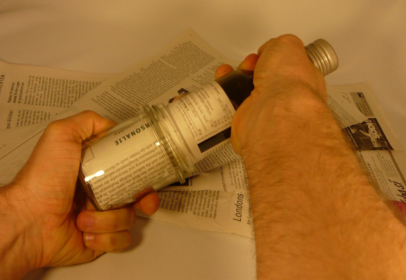 Anzuchttopf wird zwischen Flasche und Glas in Form gepresst