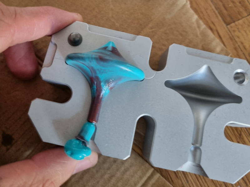 geöffnete Spritzgussform mit einem Kreisel aus Plastikmüll
